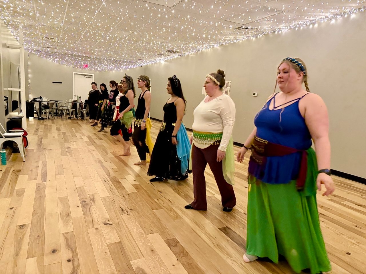 Mulheres dançando em fila no estúdio sob luzes de fada
